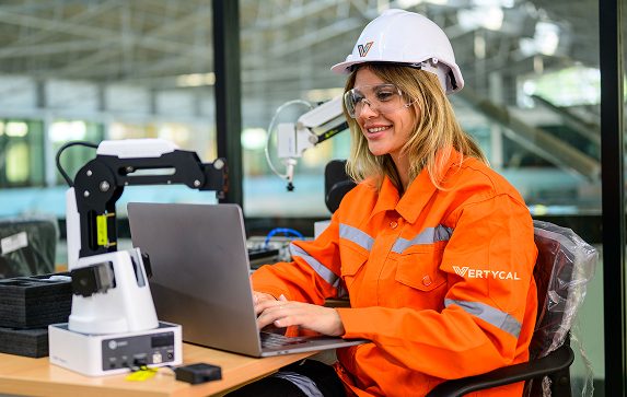 Profesional con equipo de protección trabajando junto a un brazo robótico