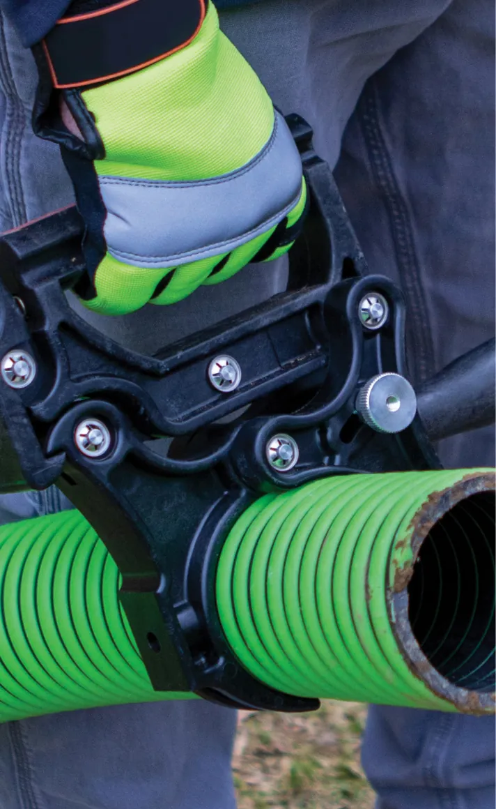 Trabajador con guantes de seguridad levantando una manguera de succión verde con una manilla Handle-Tech